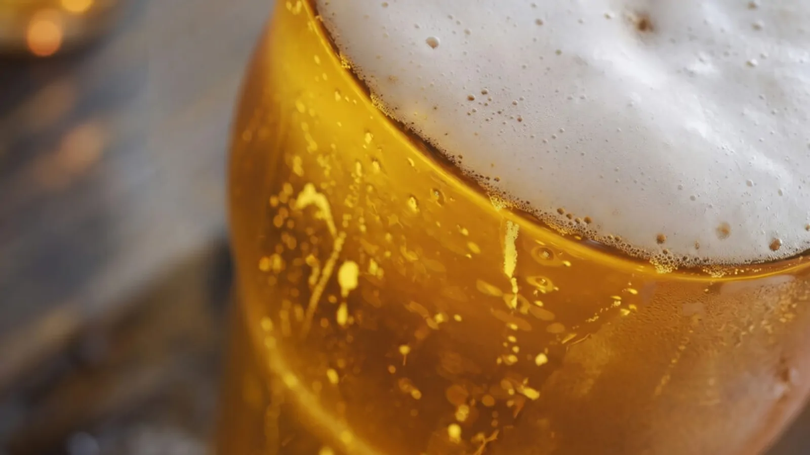 A cold glass of golden lager with a frothy head, viewed from a top-down angle